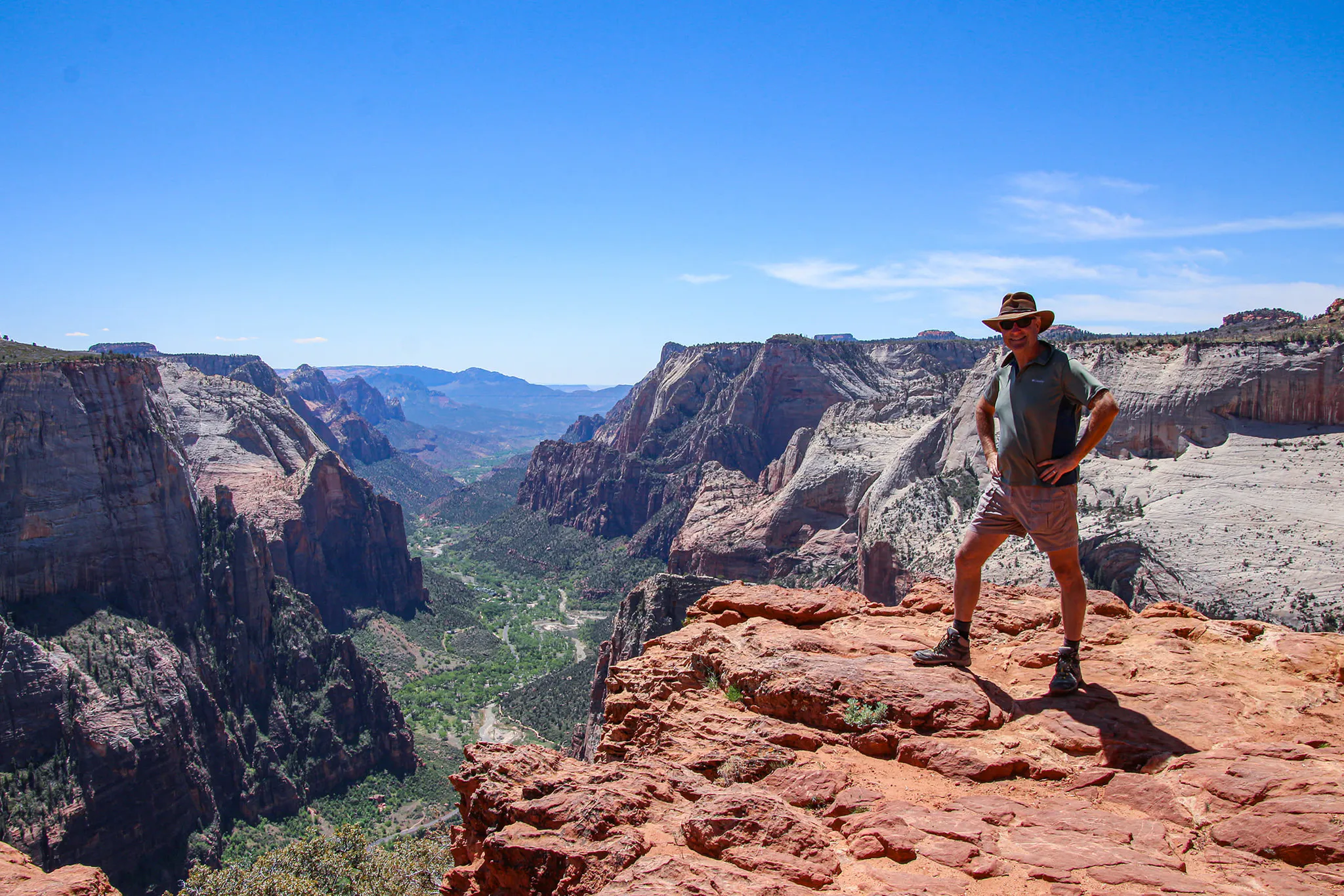 A hiker stands high above the valley floor at Observation Point in Zion National Park.
