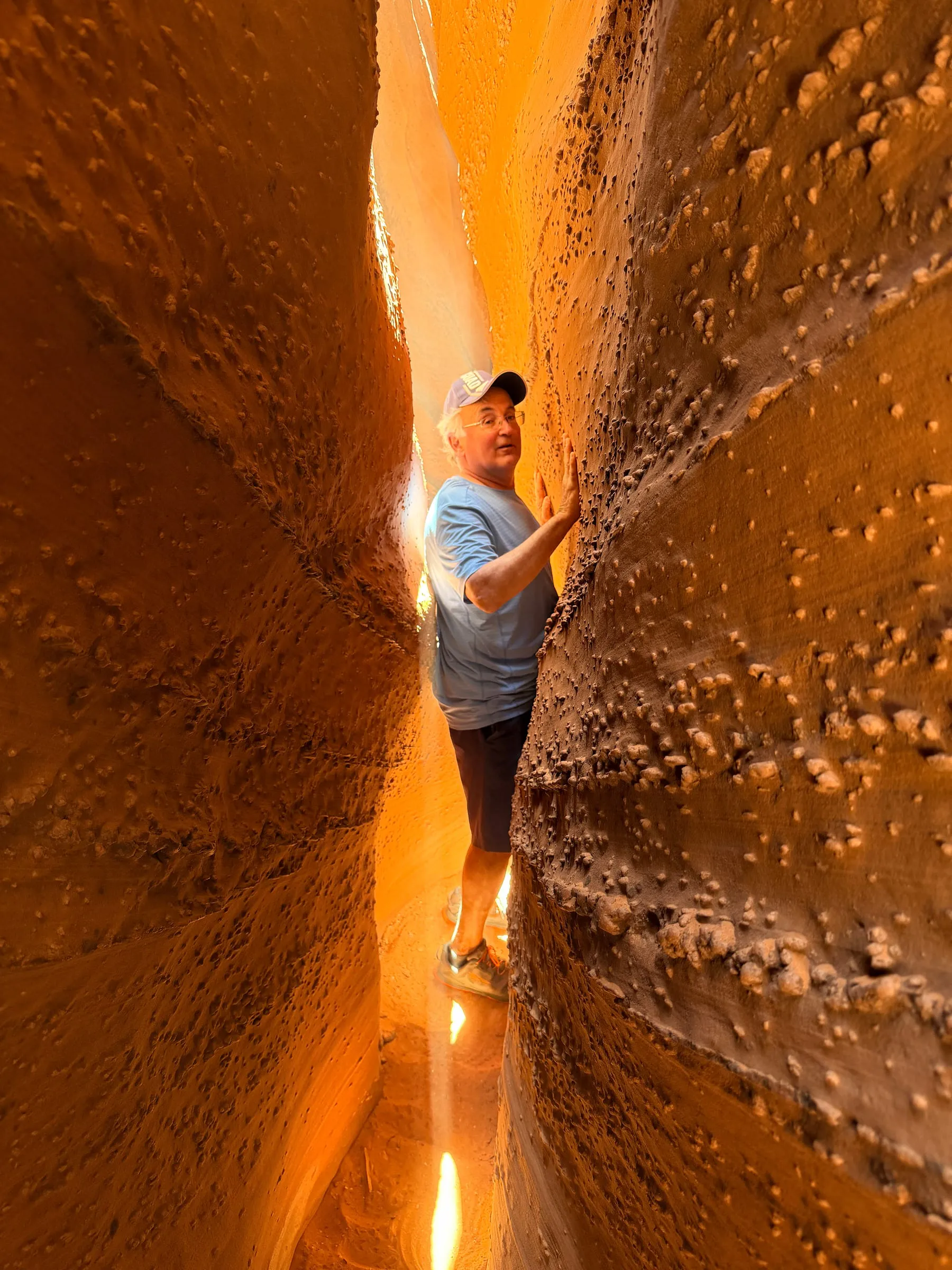 A hiker squeezing through a narrow slot canyon