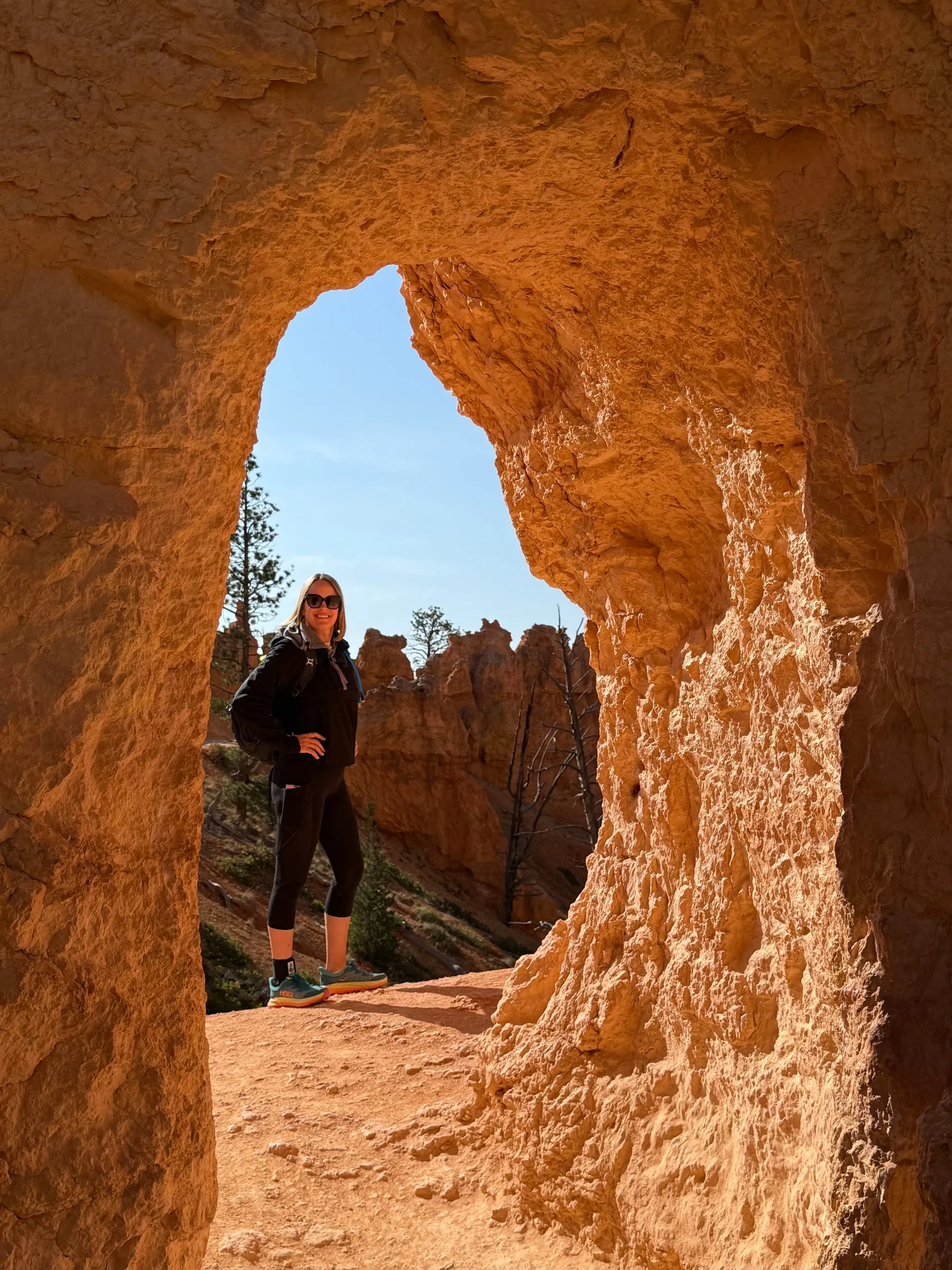 A hiker framed by a hoodoo arch on the trail in Bryce Canyon